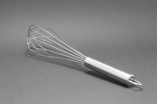 Manual hand egg beater mixer isolated on gray background