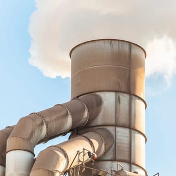 Old smokestack that emits white smoke.
