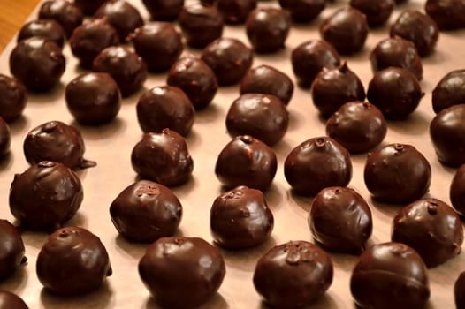 Hand-dipped, chocolate Martha Washington candy (also know as chocolate bon-bons) layed out on wax paper in rows to dry.