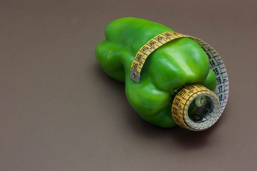 Green pepper isolated on a brown background to understand a concept to healthy eating