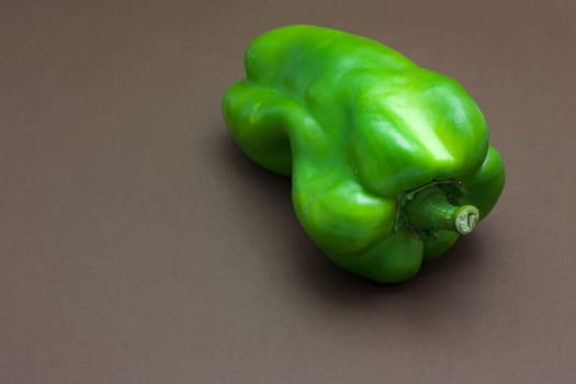 Green pepper isolated on a brown background to understand a concept to healthy eating