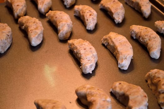 Raw cookie dough, on baking sheet ready to go in the oven. Crescent cookies in moon shapes.