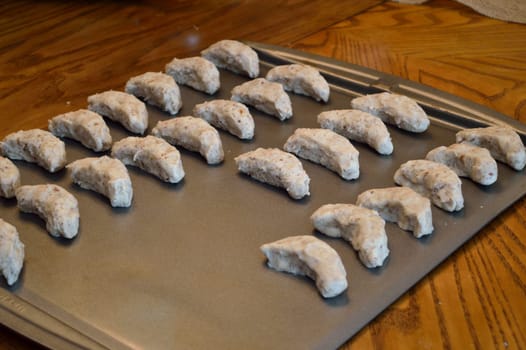 Raw cookie dough, on baking sheet ready to go in the oven. Crescent cookies in moon shapes.