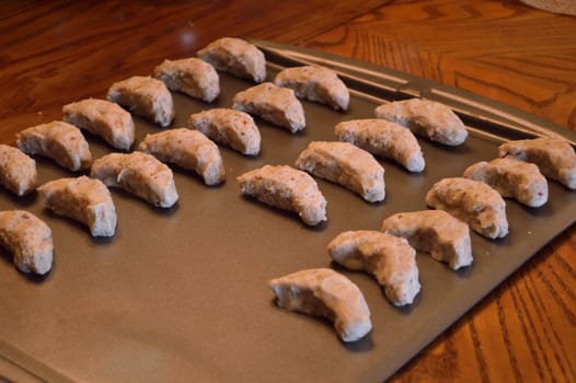 Raw cookie dough, on baking sheet ready to go in the oven. Crescent cookies in moon shapes.