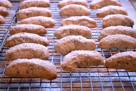 Crescent cookies, fresh out of the oven, and layed out on cooling racks to cool. Powdered sugar sprinkled on top.