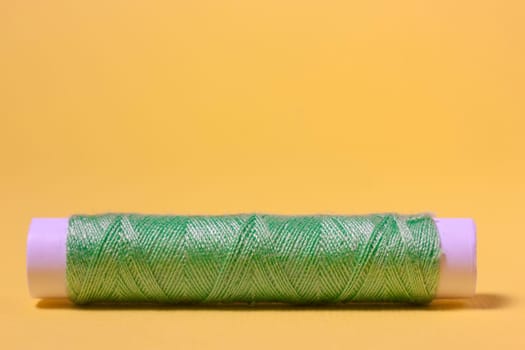 Green cotton thread on a yellow background