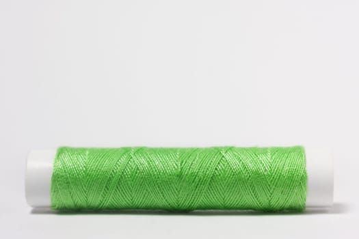 Green cotton thread on a white background
