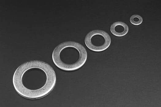 Pile of stainless steel flat washers isolated on a dark background