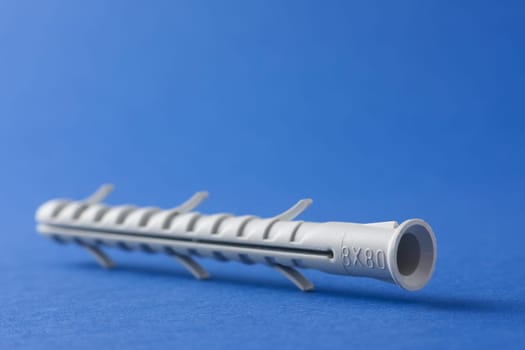 Plastic straddling dowel or rawl plug on a blue background