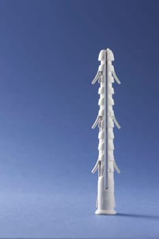 Plastic straddling dowel or rawl plug on a blue background