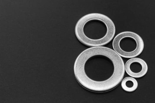 Pile of stainless steel flat washers isolated on a dark background