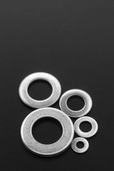 Pile of stainless steel flat washers isolated on a dark background