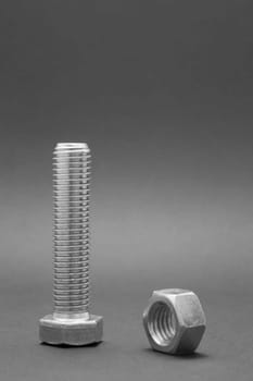 Closeup shiny steel bolt with nut on the black background