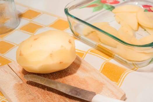 Potato and kitchen knife on a wooden cutting board
