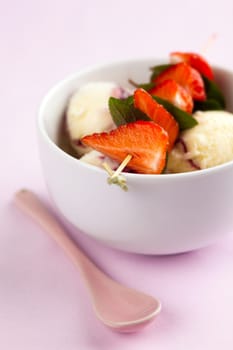 Vanilla ice cream with strawberries and mint leaves on a skewer