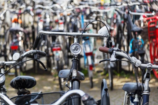handlebar of a bicycle standing between others at a bicycle parking lot