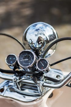 handlebar with chrome instruments and headlight of a scooter