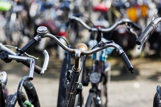 handlebar of a bicycle standing between others at a bicycle parking lot