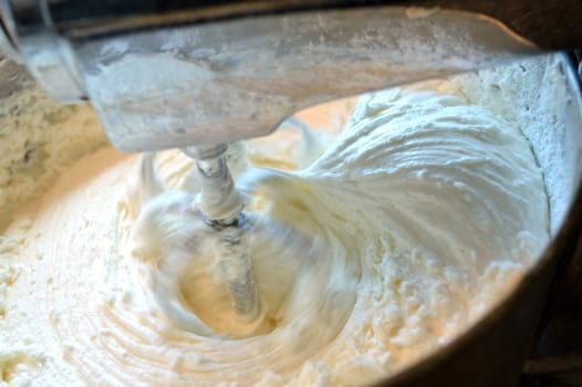 Yummy, homemade, vanilla icing in stainless steel stand mixer,  being mixed together.