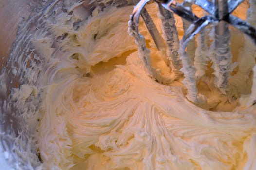Yummy, homemade, vanilla icing in stainless steel stand mixer after having been mixed together.