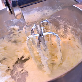Square image of creamed butter in a stainless steel stand mixer. Butter creamed for use in baking and icings.
