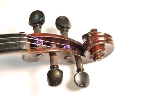 Scroll of an antique violin against a bright white background. Violin is an antique from the early 1800's in a dark stain (original finish).