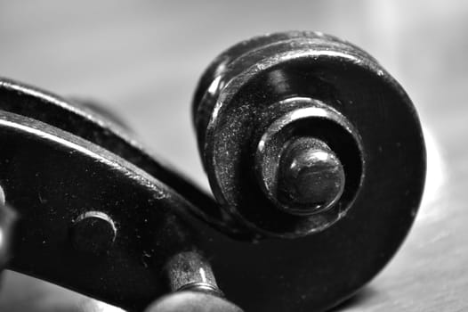 Extreme closeup shot in black and white of the scroll of an antique violin, worn and dusty.