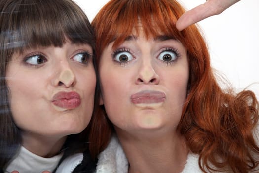 Friends making a silly face against a windowpane