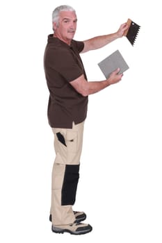 Man holding a tile and a spatula