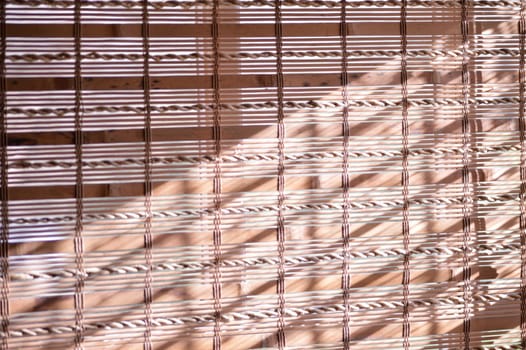Bamboo shades covering window with sunlight shining on them