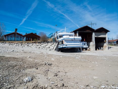 Rear view of the motor ship MS Füssen in the drained Foggen Lake at the boathouse for inspection in sunny spring weather and blue skies.