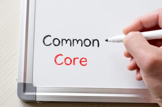 Human hand writing common core on whiteboard