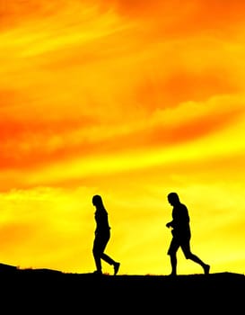 Woman and man walking one after another on a park at sunset