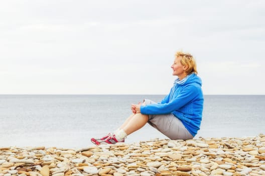 Woman sitting on the beach and looks into the distance