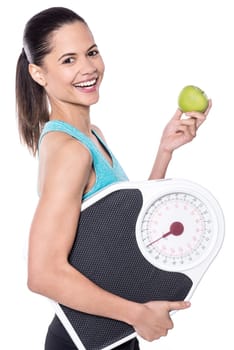 Cheerful lady holding weigh scale and green apple
