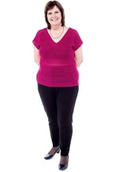 Attractive elderly woman standing with hands hidden