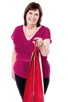 Smiling senior woman offering her red shopping bag