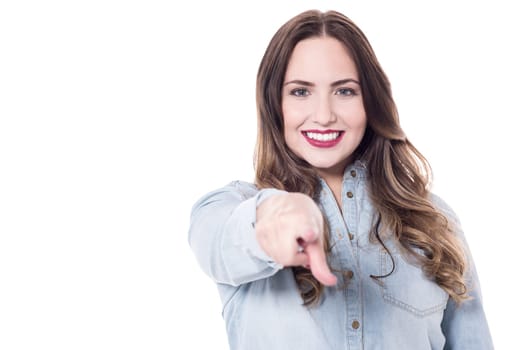 Smiling young woman pointing index finger at camera