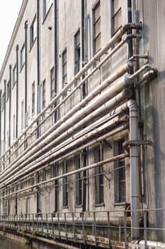 Old pipes on the wall outside of an old abandoned factory.