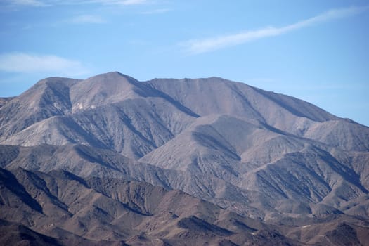 The portrait of a mountain with different and dark rock layers and faults near the Death Valley intersection.