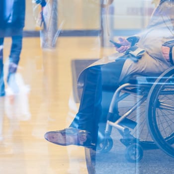 Handicapped male businessman on a wheelchair using smartphone. Disabled people active for life.