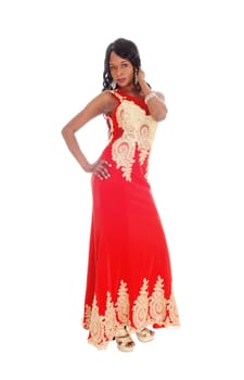 A gorgeous African American woman standing in a long red evening dress.with gold embroideries and black hair isolated for white background..