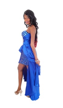 A lovely African American woman in a long blue evening dress with curly.black hair standing in profile,  isolated for white background..