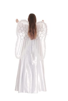 An angel in a long white satain dress with wings and long brown hair.standing from the back with arms raised isolated for white background..