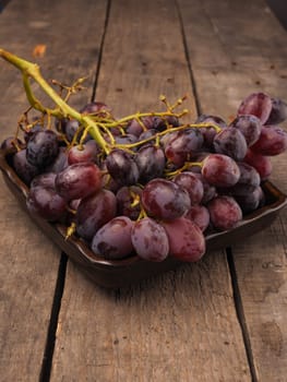 Red grapes in a rustic bowl on a wooden table