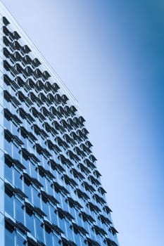 New modern high-rise steel and glass office building with large windows and open air conditioning ventilation system. Toned and filtered stock photo.