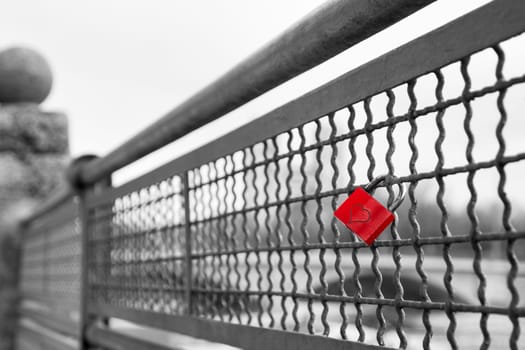 Red love lock padlock with heart on bridge symbol of true eternal love and commitment. Balck and white stock photo with selective color effect.