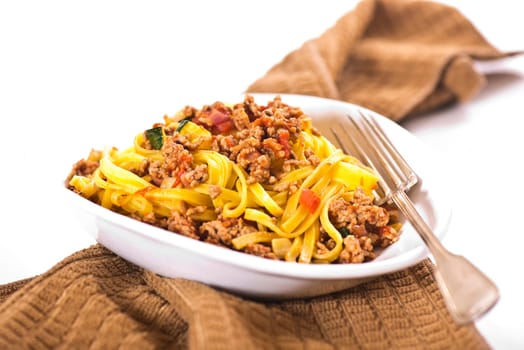 Ribbon noodles with minced meat in white peel with peppers and herbs