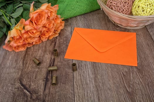 Yellow envelope, tulips and bullets on a wooden background