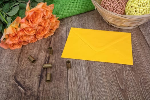 Yellow envelope, tulips and bullets on a wooden background